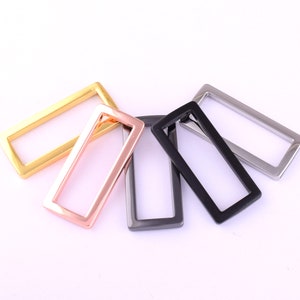 Könnte beinhalten: Vier rechteckige Metallrahmenschnallen in Gold, Roségold, Schwarz und Silber.