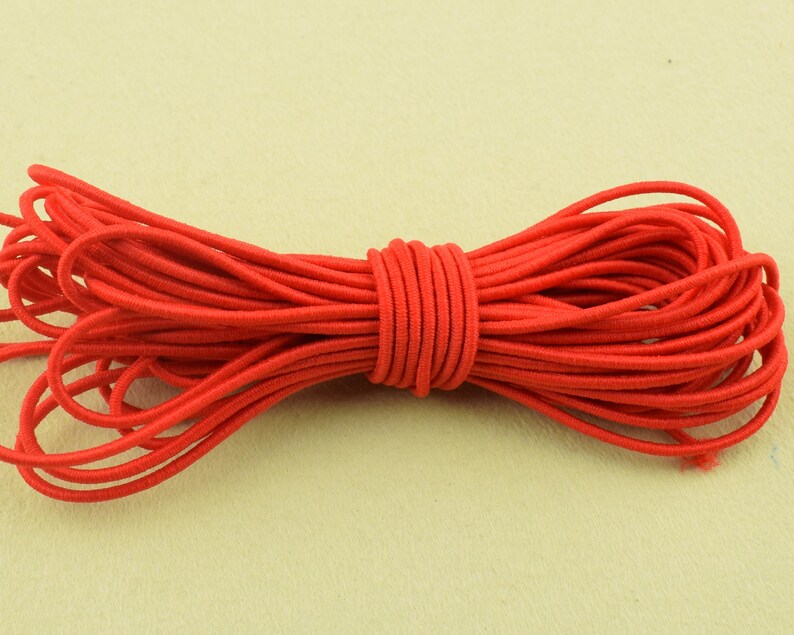 May include: A bundle of bright red elastic cord, tightly wound and ready for use. The cord is a vibrant, solid color, and appears to be made of a stretchy, durable material. The cord is likely used for crafting, sewing, or other DIY projects.