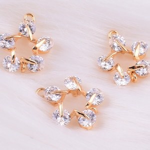 May include: Three gold-tone star-shaped charms with clear crystal accents. Each charm has five points and a loop for attaching to a necklace or bracelet.