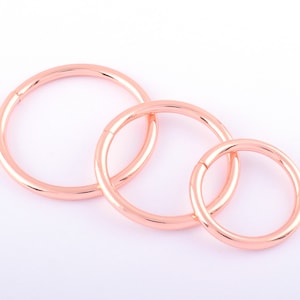 Può includere: Tre orecchini a cerchio in oro rosa di diverse dimensioni. I cerchi sono lisci e lucidi.