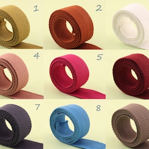 May include: Nine rolls of cotton webbing in various colors, including brown, red, pink, white, blue, and gray. The rolls are numbered 1 through 9.