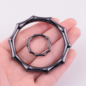 May include: Two black metal rings with a bamboo-like design. The larger ring is about 3 inches in diameter and the smaller ring is about 1.5 inches in diameter.