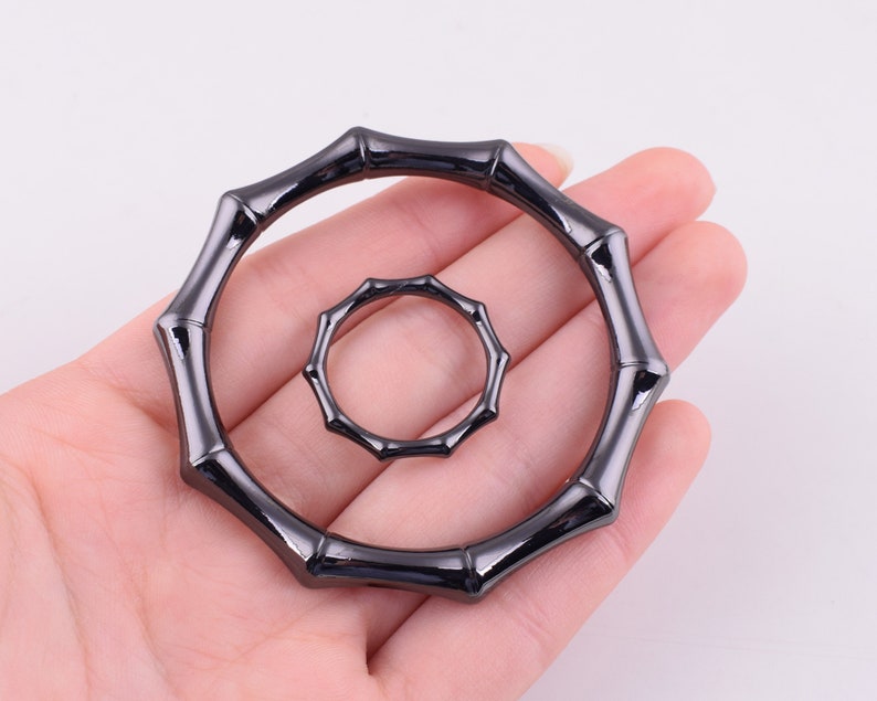May include: Two black metal rings with a bamboo-like design. The larger ring is about 3 inches in diameter and the smaller ring is about 1.5 inches in diameter.