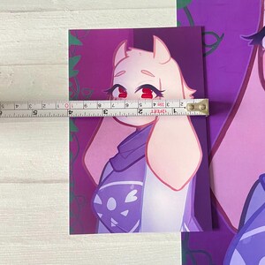Puede incluir: Una ilustraci&oacute;n digital de un personaje de dibujos animados con piel rosa, ojos rojos y cabello blanco. El personaje lleva una camisa blanca y morada con cuello blanco y una chaqueta blanca y morada. El personaje est&aacute; de pie frente a un fondo morado con enredaderas.