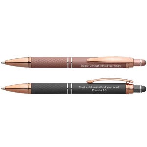 May include: Two pens with rose gold accents. One pen has a textured, mauve barrel with the text "Trust in Jehovah with all your heart." The other pen has a black, textured barrel with the text "Trust in Jehovah with all your heart. Proverbs 3:5."