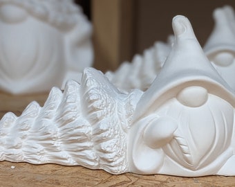 Può includere: Figurina di gnomo in ceramica bianca con cappello a punta e barba. Lo gnomo è seduto su un albero di pino in ceramica bianca.