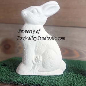 May include: White ceramic bunny figurine with a detailed design. The bunny is sitting upright with its ears perked up. Property of FoxValleyStudiosllc.com.