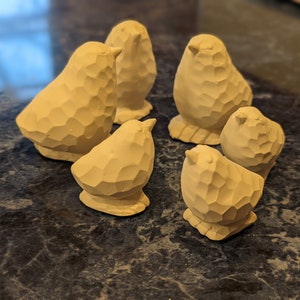 May include: A set of six small, white ceramic bird figurines with a textured surface. The birds are arranged in a circle on a dark gray surface.