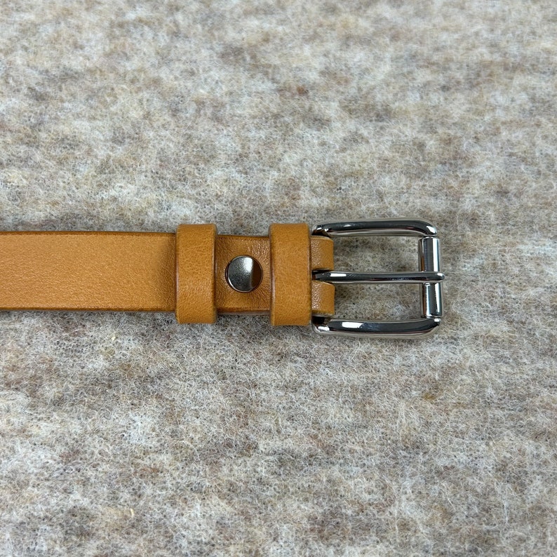 May include: A brown leather belt with a silver buckle. The buckle has a double prong design.