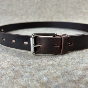 May include: A brown leather belt with a silver buckle. The belt has five evenly spaced holes for adjusting the fit.