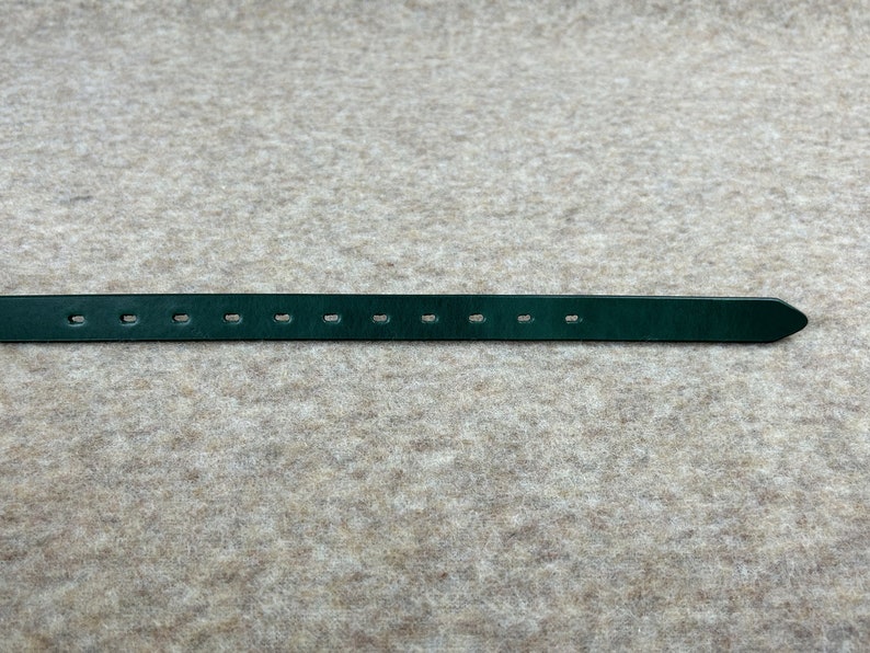 May include: A dark green leather belt with multiple evenly spaced holes for adjusting the fit.