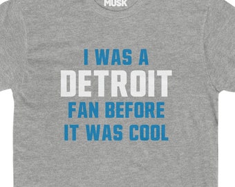 May include: A heather grey t-shirt with the text "I was a Detroit fan before it was cool" printed in blue.