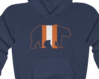 May include: A navy blue hoodie with a white bear silhouette. The bear has orange and white stripes down its back.