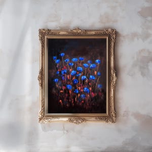 Könnte beinhalten: Gerahmter Kunstdruck mit leuchtend blauen Blumen und roten Akzenten vor dunklem Hintergrund. Das Kunstwerk ist in einem verzierten, goldfarbenen Rahmen eingefasst, der dem Stück eine elegante Note verleiht. Der Druck wird an einer strukturierten, cremefarbenen Wand präsentiert.