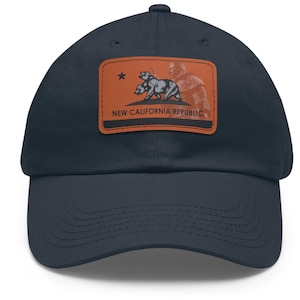 May include: A navy blue baseball cap with a brown patch featuring a three-headed bear and the text "NEW CALIFORNIA REPUBLIC".