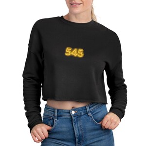 May include: Black cropped sweatshirt with long sleeves and a yellow neon number "545" printed on the front.