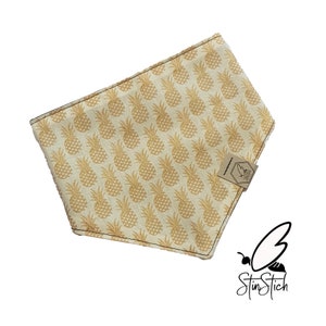 Könnte beinhalten: Ein gelbes und weißes Bandana mit einem Ananas-Muster. Das Bandana hat ein braunes Etikett mit dem Text "StitnStitch" und einem Bienenlogo.