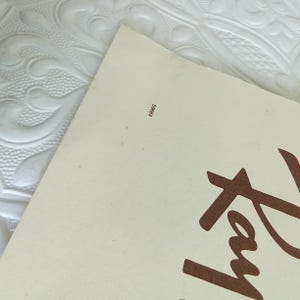 May include: A corner of a cream-colored paper with the brown text "Tex" visible. The paper has the number "S9683" printed in black in the upper left corner. The paper is on a white, textured surface.