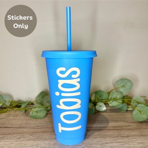 May include: A blue tumbler with a matching lid and straw. The word "Tobias" is printed vertically in a cream colour on the side of the cup. The image also includes a sticker that says "Stickers Only".