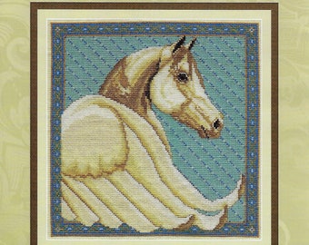 May include: A cross stitch pattern featuring a golden horse with wings against a blue background. The pattern is titled "Golden Pegasus" and is designed by Stephanie Seabrook Hedgepath. The pattern is from Pegasus Originals Inc.