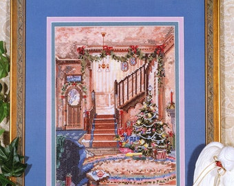 May include: A framed cross-stitch artwork titled "Marty Bell's Ready For Christmas." The image depicts a detailed interior scene with a Christmas tree, staircase, and festive decorations. The artwork is framed in gold with a blue matting.