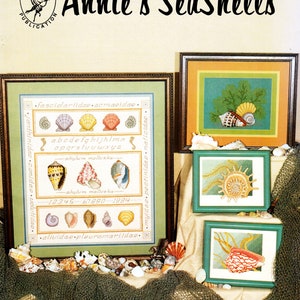 Op de afbeelding: Een ingelijst kruissteekontwerp met verschillende schelpen met de titel "Annie's SeaShells" en de tekst "Chart Collection 198" en "Designer Annie Morgan".