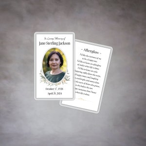 May include: A white memorial card with a floral design and a photo of a woman. The card includes the text "In Loving Memory of Jane Sterling Jackson" and the dates "October 17, 1938" and "April 29, 2024". The back of the card features a poem titled "Afterglow" about leaving a happy memory behind.