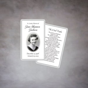 May include: A black and white memorial card with a photo of a woman and text that reads "In Loving Memory of Jane Shannon Jackson" and "December 23, 1978 January 25, 2023". The card also includes the 23rd Psalm.