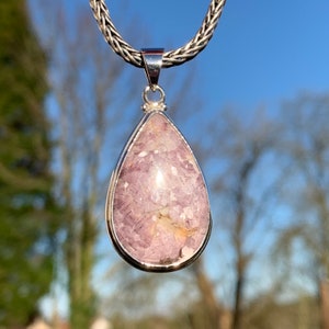 K&ouml;nnte beinhalten: Eine tropfenf&ouml;rmige Anh&auml;nger-Halskette mit einer silbernen Kette und einem rosa-wei&szlig;en Edelstein.