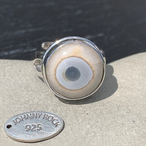 May include: A silver ring with a white and gray agate stone set in the center. The ring is marked "JOHNNY ROCK 925" on a tag.