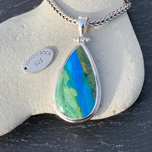 Puede incluir: Un colgante en forma de l&aacute;grima con una piedra de &oacute;palo azul y verde engastada en plata de ley. El colgante est&aacute; en una cadena de plata y tiene una etiqueta que dice "Johnny Rock 925".