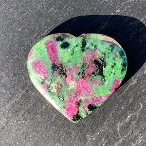 Könnte beinhalten: Herzförmiger Stein in Grün, Pink und Schwarz mit einem wirbelnden Muster.