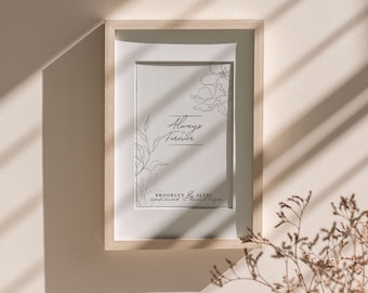 May include: A framed print with a simple line drawing of flowers and the text "Always & Forever" with the names "Brooklyn & Alexi" below. The frame is light wood and the print is on white paper.