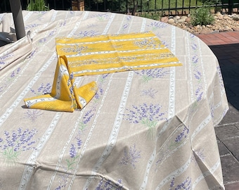May include: A round, beige tablecloth with a lavender floral pattern and yellow striped napkins. The tablecloth has a striped pattern with a white border and the napkins are folded into a triangle shape.