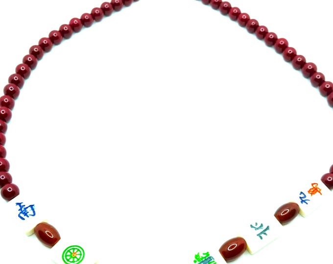 Red bead necklace with small, bone, mahjong tiles.