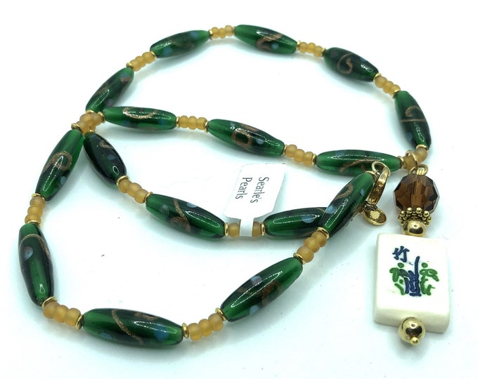 Delicate necklace with glass beads and a pendant made of a crystal and a bone flower mahjong tile.
