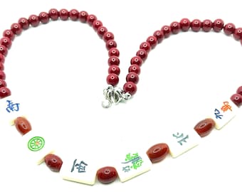 Red bead necklace with small, bone, mahjong tiles.