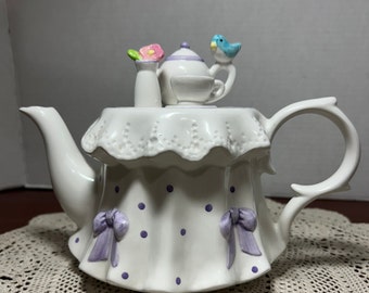 Tetera vintage "The Tea Party" de Teleflora, lazos y lunares de color morado claro, pájaro azul, flor rosa