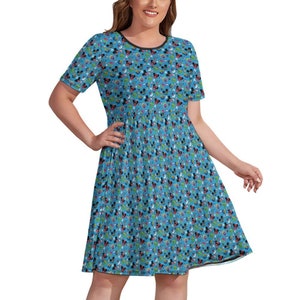 May include: A blue short-sleeved dress with a pattern of colorful cartoon characters. The dress has a round neckline and a slightly flared skirt.