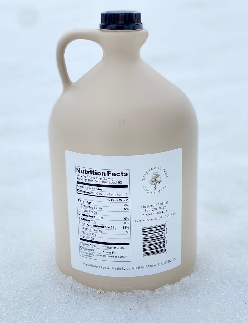 May include: A brown plastic jug of maple syrup with a black lid and a white label with the words "Nutrition Facts" and "Nott Family Farm Choice Maple" printed on it. The label also includes the company's address, phone number, and website. The jug is sitting on a white surface.