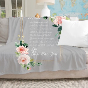 May include: A gray fleece throw blanket with a floral design and a gold frame. The blanket has a poem printed on it that reads "Saw the day we were small, Fill the days in store till, Saw the day we began understanding things, Fill the days in store till, Saw the day you got your wings, Your love has never fallen short, You are our faithful, constant support, Let it be a blanket hug as we do more well,  Love, Collan, Tim & Jason".
