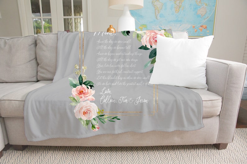 May include: A gray fleece throw blanket with a floral design and a gold frame. The blanket has a poem printed on it that reads "Saw the day we were small, Fill the days in store till, Saw the day we began understanding things, Fill the days in store till, Saw the day you got your wings, Your love has never fallen short, You are our faithful, constant support, Let it be a blanket hug as we do more well,  Love, Collan, Tim & Jason".