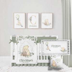 May include: A nursery set featuring Winnie the Pooh illustrations. The set includes framed wall art, a crib sheet, a blanket, and a pillow. The artwork and textiles feature a soft color palette of beige, green, and white, with the name "Christopher" displayed.
