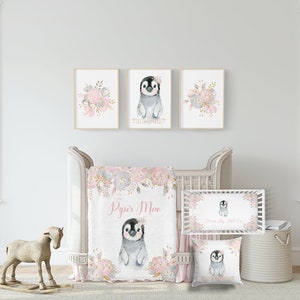 May include: A nursery bedding set with a pink and gray color scheme featuring a penguin with a floral crown. The set includes a blanket, a pillow, and a crib sheet. The blanket and pillow feature a floral design with gold accents. The crib sheet has a floral border and the text "Dream Big Little One".