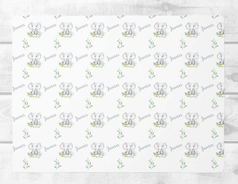 May include: White fabric with a repeating pattern of a gray elephant sitting in green grass with the name "James" written in gray script.