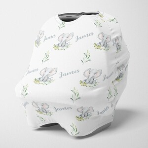 May include: White car seat cover with a repeating pattern of gray elephants, green leaves, and the name "James".