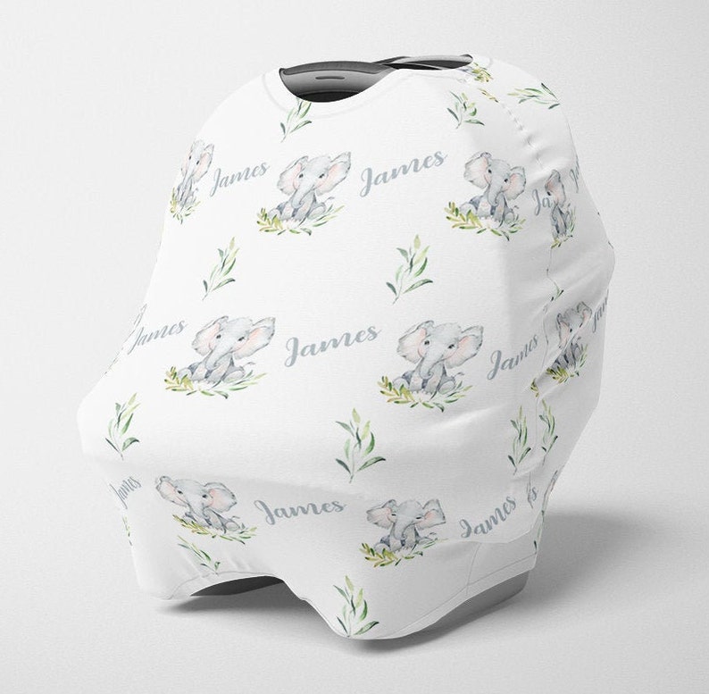May include: White car seat cover with a repeating pattern of gray elephants, green leaves, and the name "James".