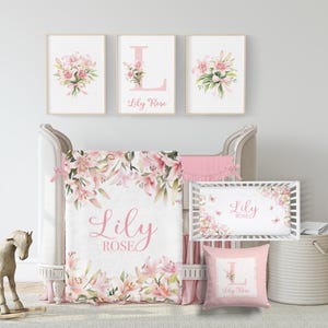 May include: A nursery set featuring a crib, bedding, and wall art. The set includes a blanket, crib bumper, and pillow, all adorned with pink lilies and the name "Lily Rose." Three framed prints hang above the crib.