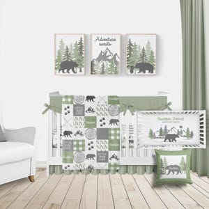 May include: A nursery set with a woodland theme. The set includes framed art, a crib bumper, a blanket, and a pillow. The art features bears, trees, and the phrase "Adventure Awaits." The crib bedding has bear and paw print patterns.