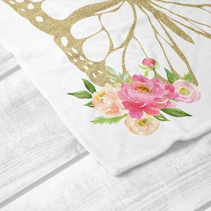 Puede incluir: Una tela blanca con un dise&ntilde;o de mariposa de purpurina dorada y flores de acuarela rosa y melocot&oacute;n.